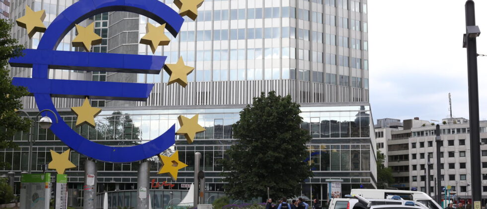 Großes Eurozeichen steht vor einem Bankenhochhaus in Frankfurt.